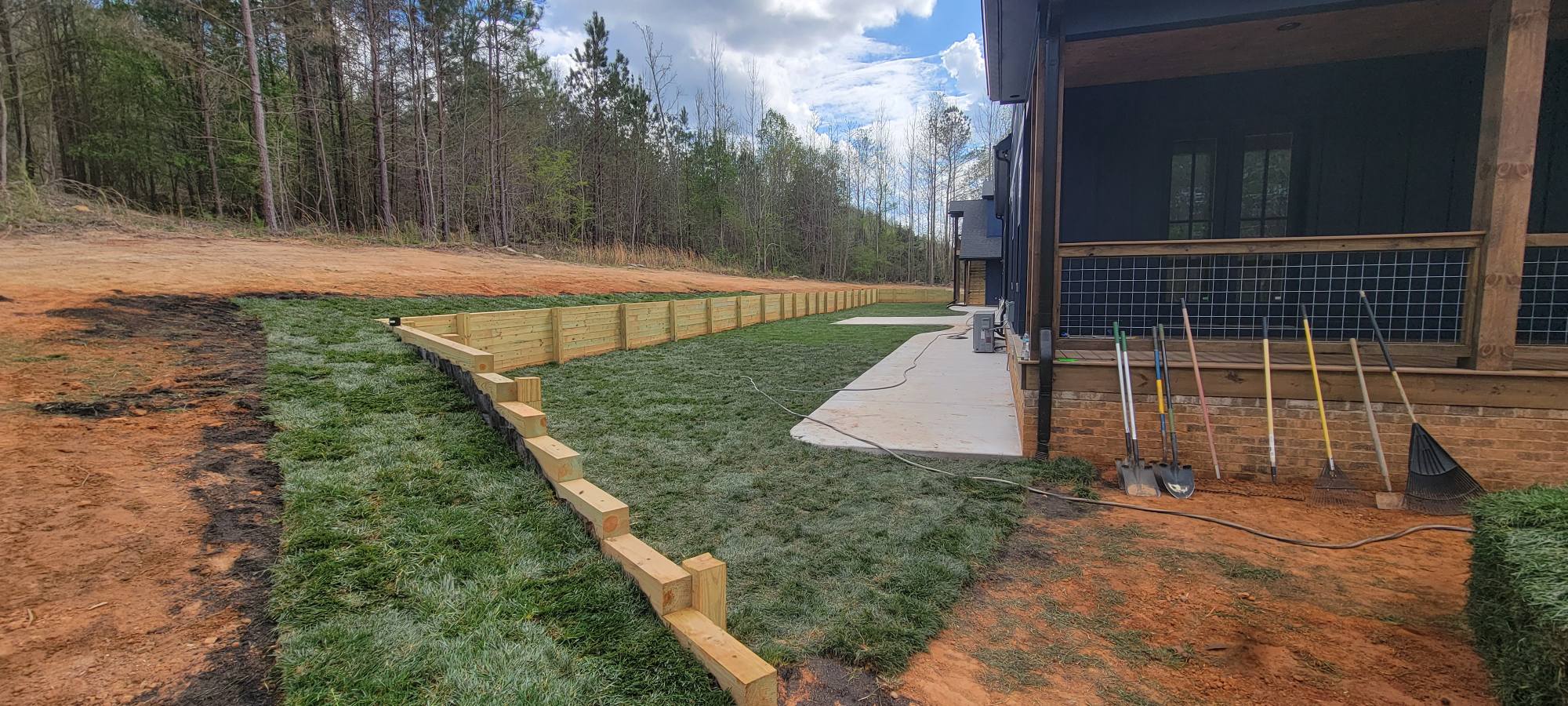 Backyard after — graded, retained with timber wall, fresh sod