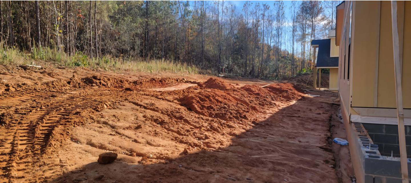 Backyard before — raw red clay soil, rough grade