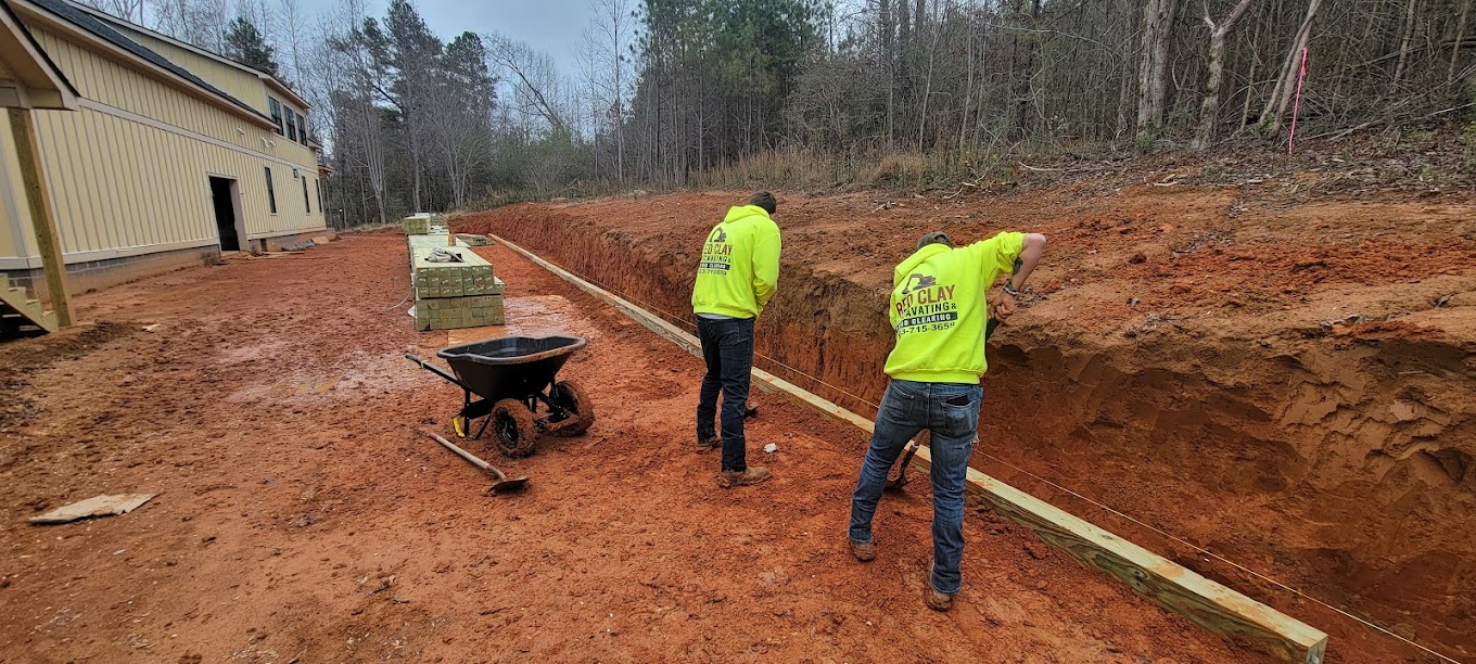 Red Clay Excavating crew working on a retaining wall in red clay soil